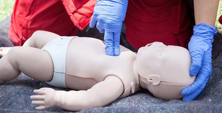 Someone giving chest compressions to a dummy baby