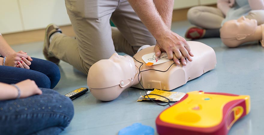 A man giving chest compressions to a dummy