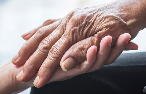 Elderly patient holding doctors hand