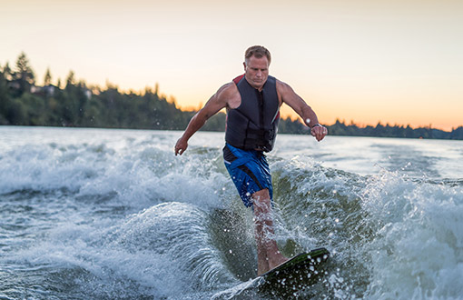 A middle aged man wakeboarding