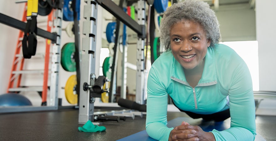 A senior woman smiling while doing planks