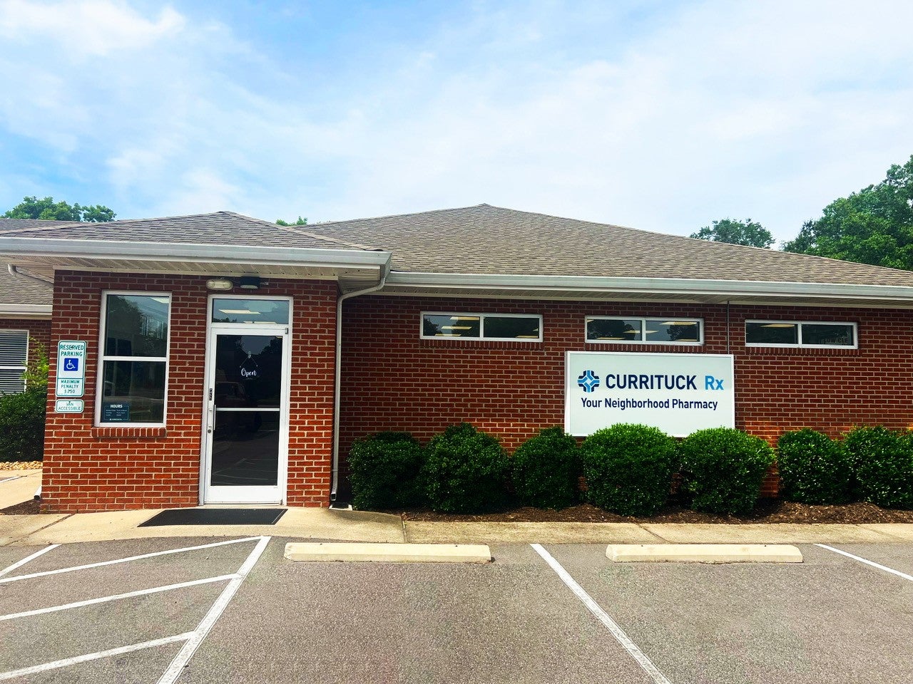 Front of Currituck Rx building with sign, front door and shrubbery