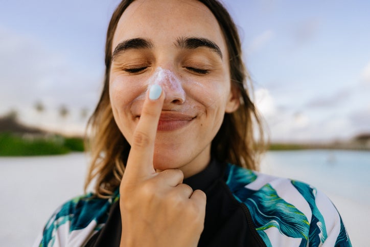 a young woman putting on sunscreen