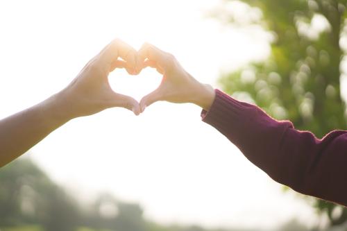 two women making a heart with their hands