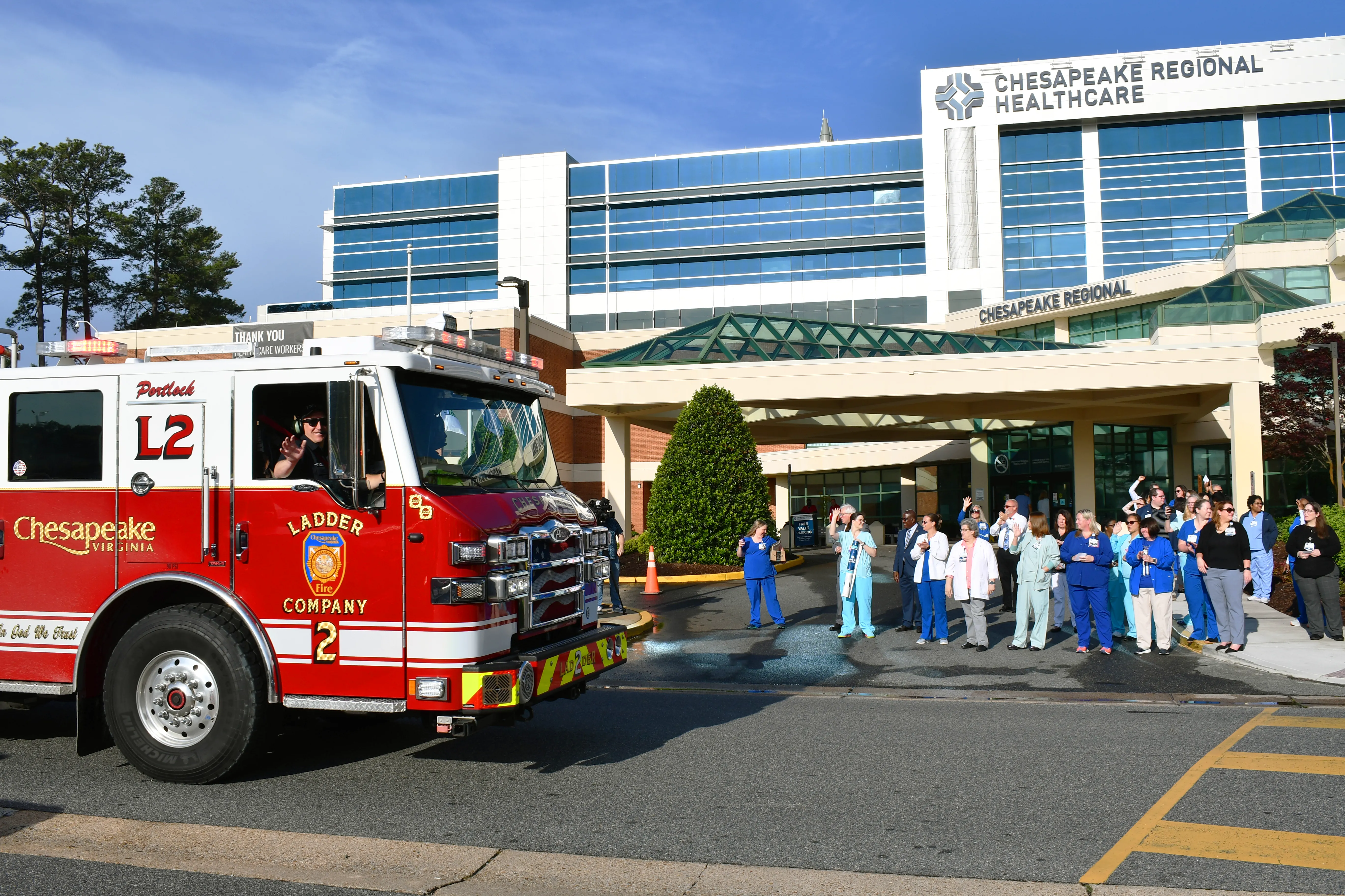 Nurses outside hospital watching emergency vehicle parade