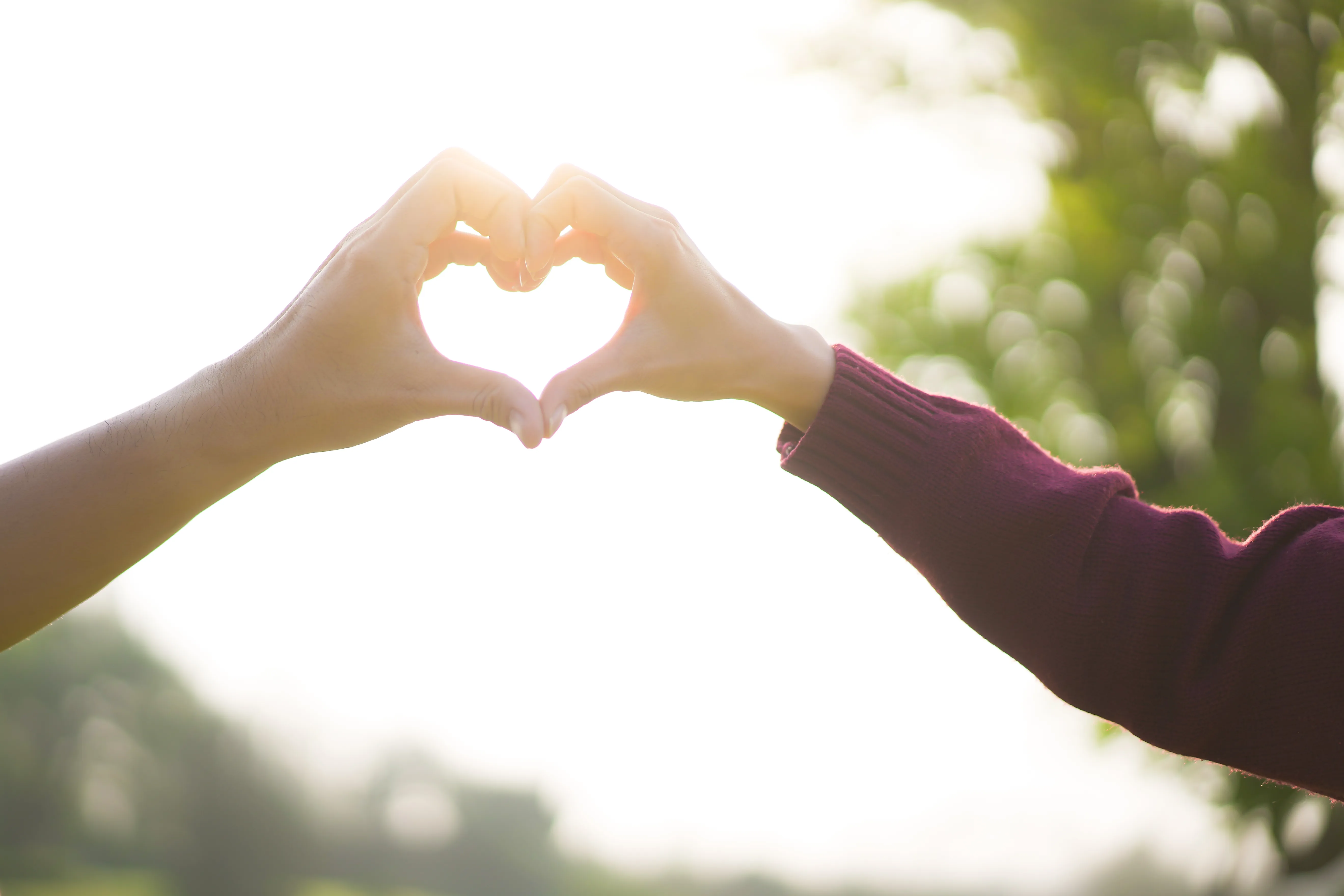 two women making a heart with their hands